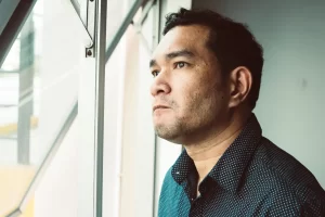 Stressed man looking out a window, reflecting confusion between ADHD and anxiety symptoms in men