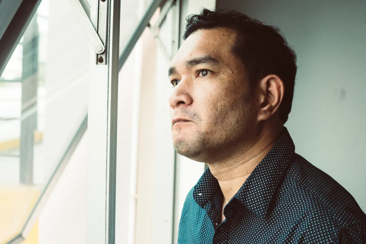 Stressed man looking out a window, reflecting confusion between ADHD and anxiety symptoms in men