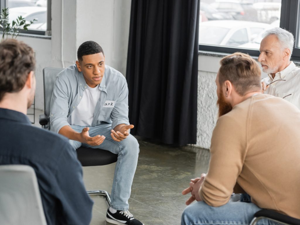 Person sitting quietly in a bright group therapy room during their first week in a partial hospitalization program